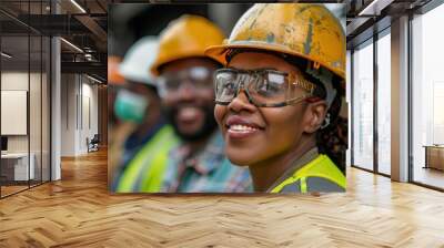 A group of multi-ethnic workers at a construction site wearing hard hats, safety glasses, and reflective clothing, smiling and conversing Wall mural