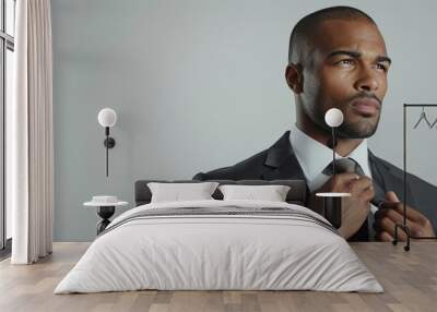 A man in a sleek suit, adjusting his tie against a white background, showcasing modern elegance Wall mural