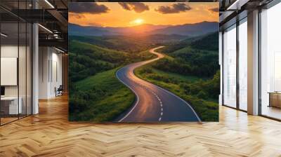 A winding asphalt highway stretching through lush green mountains under a dramatic sunset sky, with vibrant clouds, capturing the beauty of a serene road journey. Wall mural