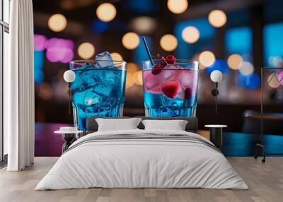 Two blue cocktails with ice and fruit, one with raspberries, in a bar setting with blurred lights. Wall mural