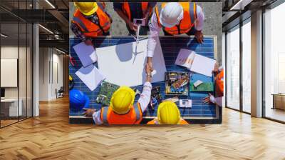 Holding hands top view of Architectural engineers working on solar panel and his blueprints with Solar photovoltaic equipment on construction site. meeting, discussing, designing Wall mural