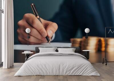 close-up of hand signing a contract with gold coins in the background - business success, investment, wealth, and financial growth concept. Wall mural