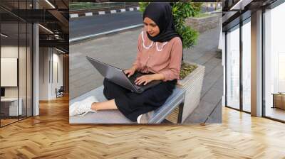 Portrait of Arab business Women working on laptop sitting at city park. Wall mural