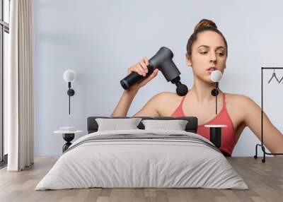 Electric massager gun in hand massages your muscles. Sport recovery concept Wall mural