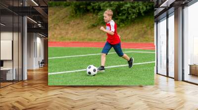 Football soccer training for kids. Boy running and kicking soccer ball. Young boy improving soccer skills Wall mural