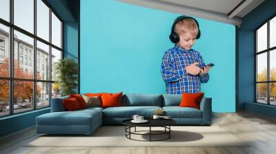 Funny little boy playing video game on cellphone, children entertainment on blue background. Wall mural