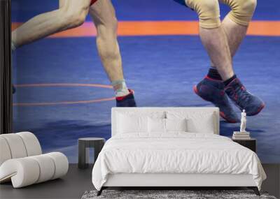 Two strong wrestlers legs  on a blue wrestling carpet in the gym Wall mural