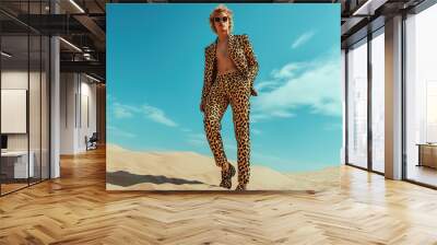 High fashion concept. Portrait of fashionable male model wearing luxurious animal print clothing among sands under the blue sky. Luxury brands campaign style. Banner. Outdoor shot Wall mural