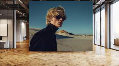 High fashion concept. Зortrait of fashionable male model with blond hair walking in luxurious clothing among sands under the blue sky. Luxury brands campaign style. Text space Wall mural