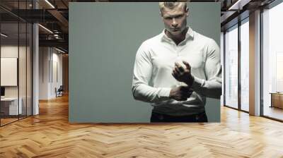 Male fashion, beauty concept. Portrait of brutal young man with short wet blond hair wearing white shirt, posing over gray background. Classic style. Copy-space. Studio shot Wall mural