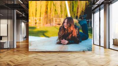 Beautiful caucasian female posing laying in a park Wall mural