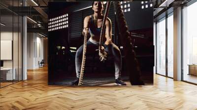 Woman training with battle rope in cross-training gym Wall mural