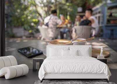 Coffee cup , mobile phone and sugar cup on stone table with sunlight in garden background Wall mural