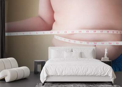 Fat boy with overweight checking out his weight isolated on white background Wall mural