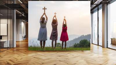 Children praying to the GOD while holding a crucifix symbol with bright sunbeam on the mountain Wall mural