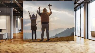 Christian, Christianity, Religion copy space background. Human praying and holding christian cross for worshipping God at sunset background. Wall mural