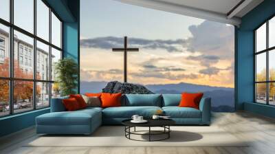 Christian cross on top rock mountain with bright sunbeam on the colorful sky background. Christian background concept Wall mural