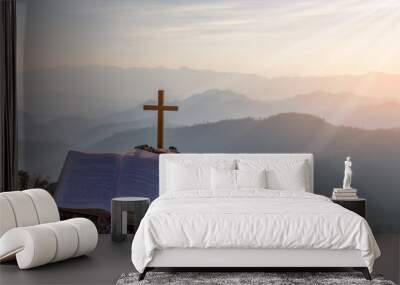 crucifix symbol and bible on top mountain with bright sunbeam on the colorful sky background Wall mural