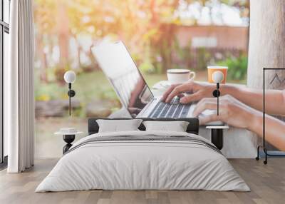 hand using laptop on wooden table in cafe Wall mural