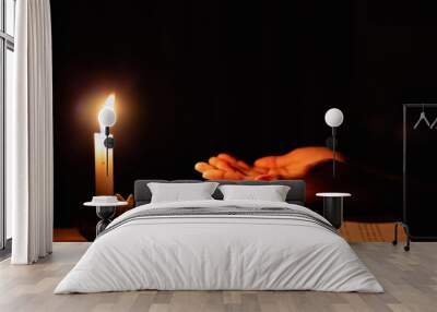 Human praying to the GOD while with a crucifix symbol with lighting candle at night time. Wall mural