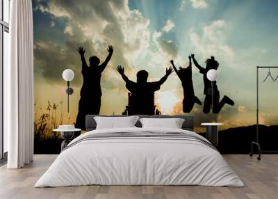 Silhouette happy family with wheelchairs looking sunset on mountain. Wall mural