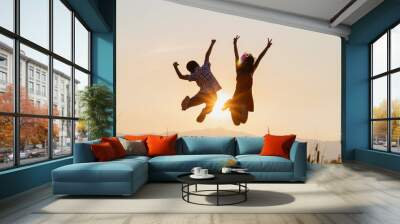 Silhouette of happy children jumping playing on mountain at sunset time Wall mural