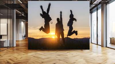 Silhouette three people jumping on mountain sunset sky background. Wall mural