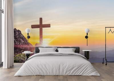 Silhouettes of crucifix symbol on top mountain with bright sunbeam on the colorful sky background Wall mural