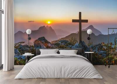 Silhouettes of crucifix symbol on top mountain with bright sunbeam on the colorful sky background Wall mural