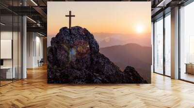 Silhouettes of crucifix symbol on top mountain with bright sunbeam on the colorful sky background Wall mural