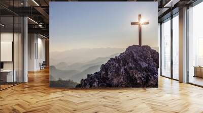 Silhouettes of crucifix symbol on top mountain with bright sunbeam on the colorful sky background Wall mural