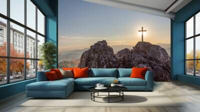 Silhouettes of crucifix symbol on top mountain with bright sunbeam on the colorful sky background Wall mural