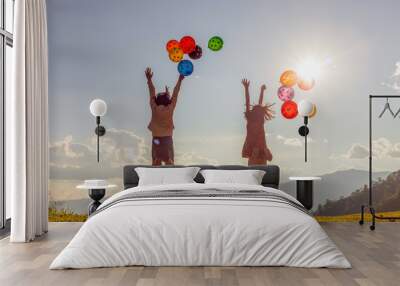 Two cute little girls playing on mountain park with air balloons at sunset. Best friends. Wall mural