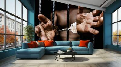 Young man desperate to catch the iron prison,prisoner concept,Handcuffed hands of a prisoner in prison, Male prisoners were severely strained in the dark prison, violence,  Wall mural