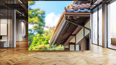 A close-up of a traditional Japanese house with a brown roof and wooden beams, with a blue sky and green trees in the background. Wall mural