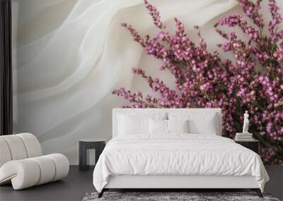 A delicate arrangement of pink flowers on a soft white fabric background. Wall mural