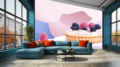 A delicious berry tart with whipped cream on a white pedestal against a pink and purple background. Wall mural