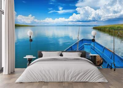 A serene view from a blue boat on calm waters, surrounded by lush greenery and clouds. Wall mural