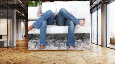 a couple in jeans using white laptops on a white sofa Wall mural