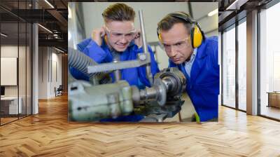 Apprentice protecting ears from noisy machine Wall mural