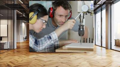 apprentice standing at drill press and listening to her mentor Wall mural