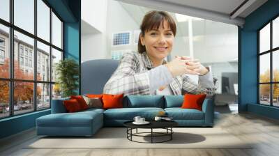 brunette woman in office with arms crossed Wall mural