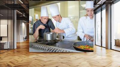 Chef checking work of trainee cooks Wall mural