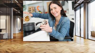 disabled woman in wheelchair preparing meal in kitchen Wall mural