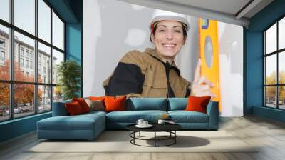 female builder checking work with spirit level Wall mural