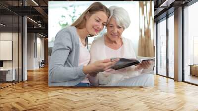 grandmother and granddaughter looking at magazine Wall mural