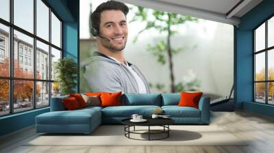 happy young man with headset and laptop Wall mural