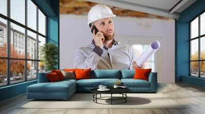 male architect talking on smartphone holding rolled up plans Wall mural