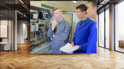 Man showing equipment to two apprentices Wall mural