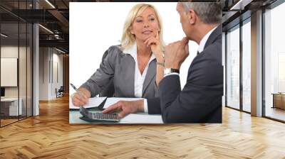 Mature business couple at a desk with a calculator Wall mural